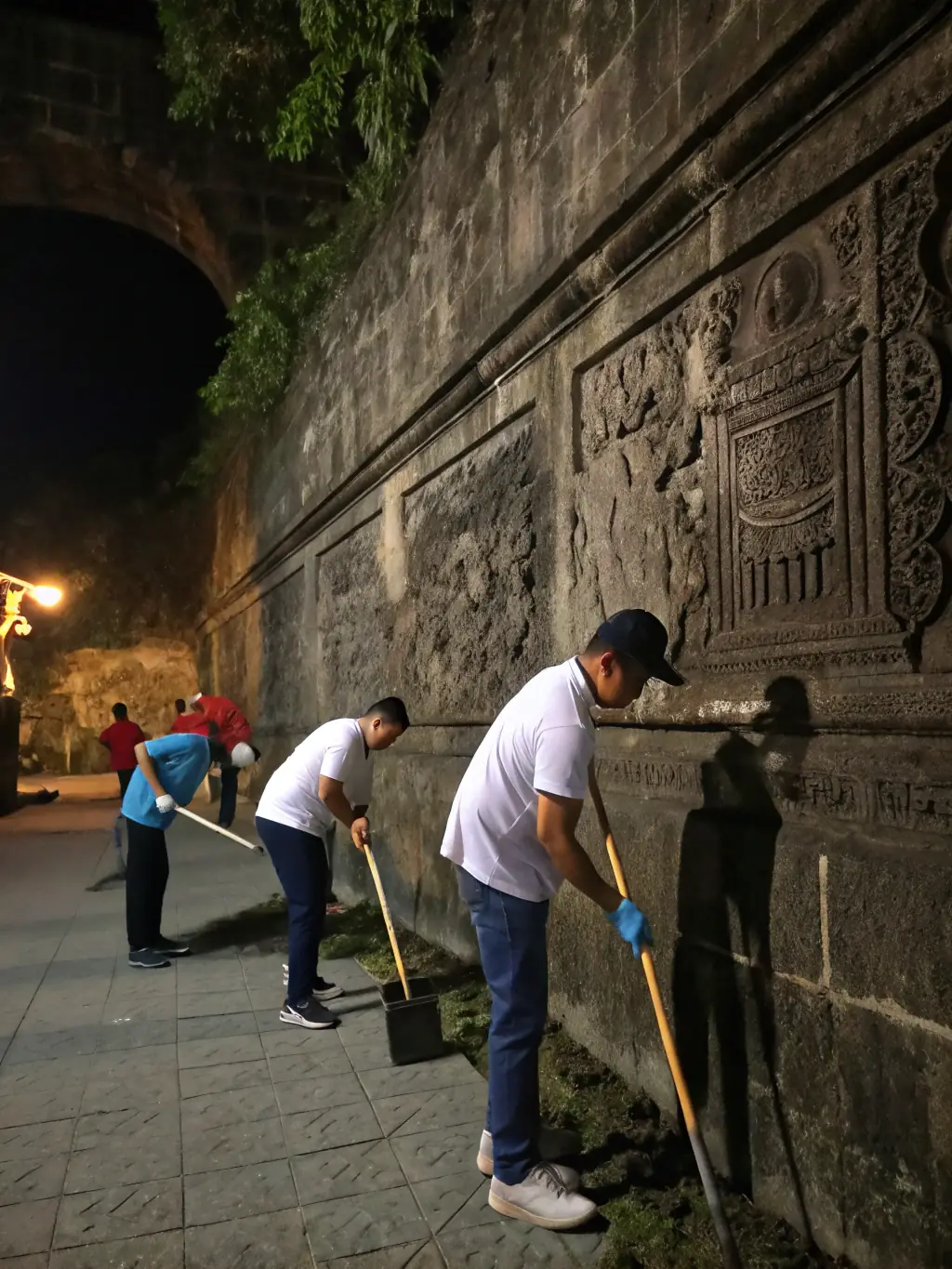 A photograph capturing a group of volunteers meticulously cleaning and restoring an ancient stone wall, part of Vernusse's historical fortifications, under the guidance of a conservation expert.